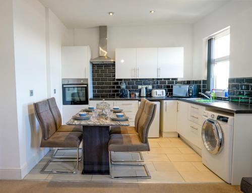 a kitchen with a table and chairs in a kitchen at Zeenat Central Bury - Modern 2BR with Free Parking Sleeps 6 in Bury
