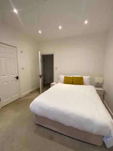 a bedroom with a large white bed with a yellow pillow at Marble House in Edgware