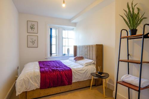 a small bedroom with a bed and a window at Zeenat Central Bury - Modern 2BR with Free Parking Sleeps 6 in Bury