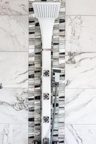 a glass revolving wine rack in a white marble wall at Raglan Travellers Rest Coastal Retreat in Raglan