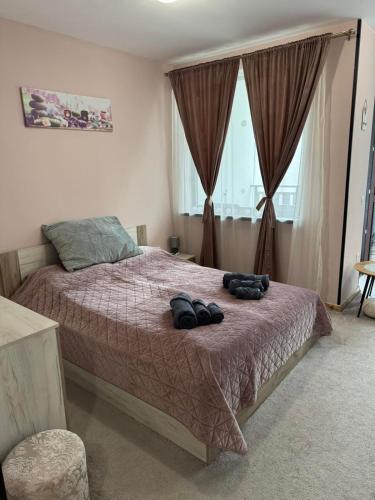a bedroom with a bed with two pairs of shoes on it at Borovetz Gardens MVS Apart E28 in Borovets