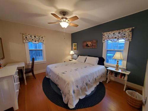 a bedroom with a bed and a table and two windows at Pleasant Brook Cottage in Roxbury