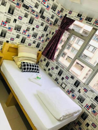 a bed in a room with a wall with a window at Rhine Guest House in Hong Kong