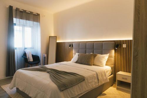 a bedroom with a large bed and a window at Central Charm Azores in Ribeira Grande