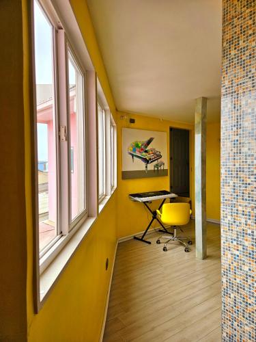 an office with yellow walls and a desk and windows at Hostal Florida Valpo in Valparaíso