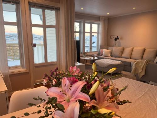 House with a beautiful seaview في ترومسو: غرفة معيشة مع طاولة عليها زهور