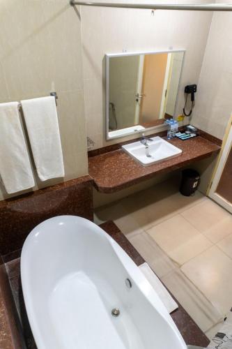 Un baño con bañera blanca y lavabo. en Muara Hotel and Mall Ternate, en Ternate