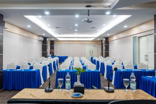 una sala de conferencias con mesas azules y sillas con gafas en Muara Hotel and Mall Ternate, en Ternate