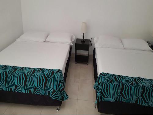 two beds sitting next to each other in a room at Hotel Septima Avenida in Neiva
