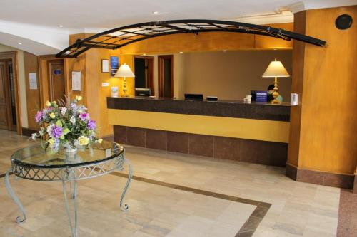 a lobby with a reception desk and a table with flowers at Hafersons Inn Hotel Suites in Madero