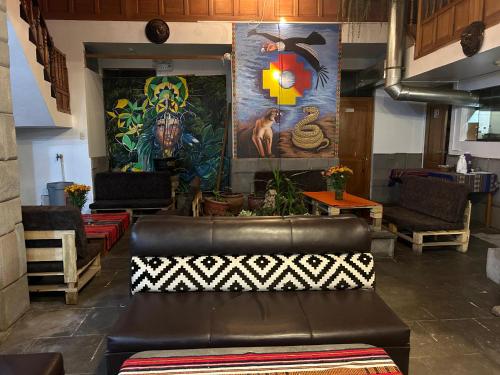 a leather couch in a room with paintings on the wall at Nafis Casona Apu Linli Pisac in Pisac