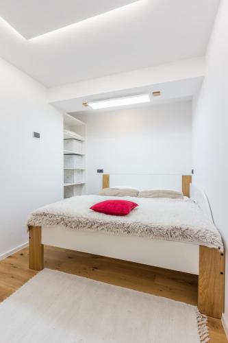 a white bedroom with a bed with a red pillow at Charming A&S Pohorje Apartments in Pohorje