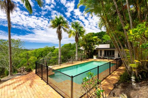 a pool with a fence and palm trees at Grande Eden Estate - Main House in Bilambil