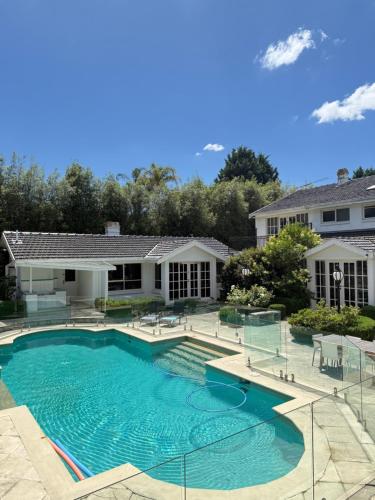 a swimming pool in front of a house at Stunning White House Luxury Retreat In Templestowe in Templestowe