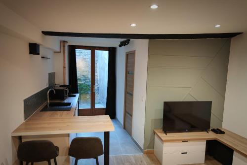 a room with a desk with two chairs and a television at Studio cosy centre ville in Besançon