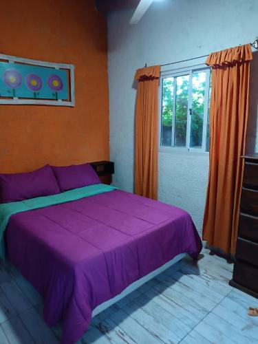 a bedroom with a purple bed and a window at MONOAMBIENTES LOS SAUCES in Mina Clavero