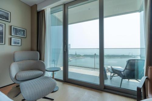 a living room with a chair and a large window at Sheraton Rizhao Hotel in Rizhao