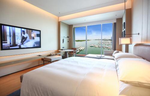 a bedroom with a large white bed and a large window at Sheraton Rizhao Hotel in Rizhao