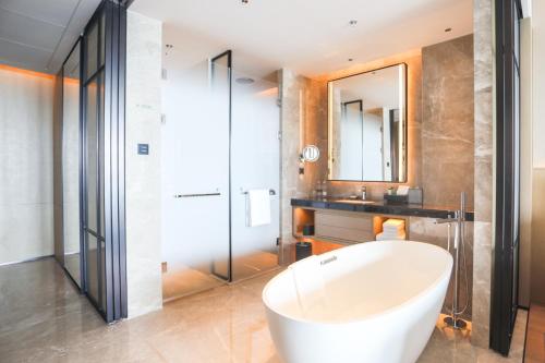 a bathroom with a tub and a sink and a mirror at Sheraton Rizhao Hotel in Rizhao