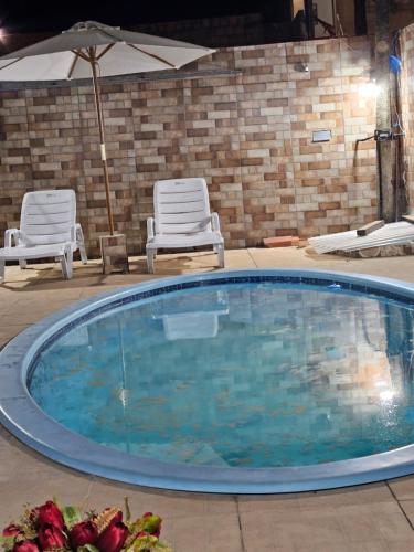 a large swimming pool with two chairs and an umbrella at casa de Praia in Goiana