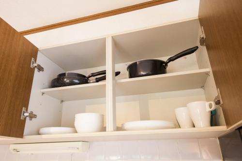 a cupboard filled with dishes and pots and pans at 10 min walk to the beach Kujukuri house for 14 ppl in Hasunuma