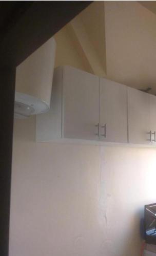 a kitchen with white cabinets on the wall at La Perla un nid douillet porte bonheur inoubliable in Ifrane
