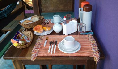a wooden table with plates and utensils on it at Pousada O Canto das Sereias in Trindade