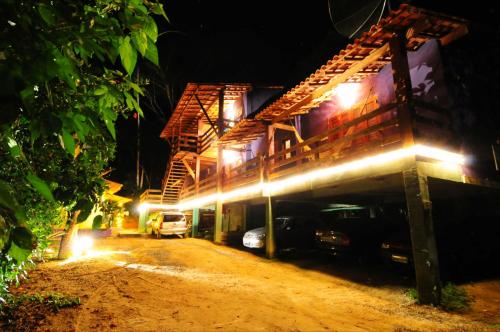 a building with cars parked on a dirt road at night at Pousada O Canto das Sereias in Trindade