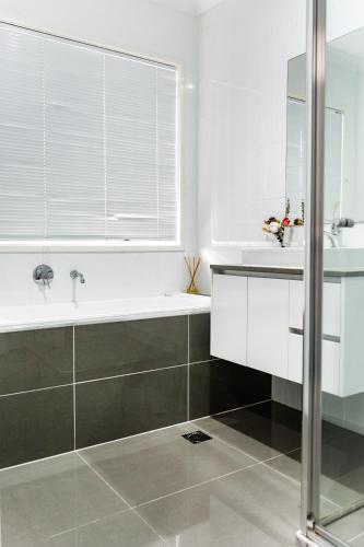 a white bathroom with a tub and a sink at Standard Queen Room in Gregory Hills - Quaint Spot - Shared Bathroom in Gledswood Hills