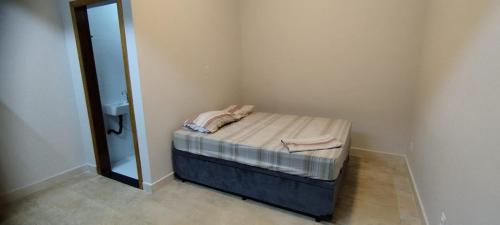 a small bed in a room with a mirror at Suítes independentes com acesso independente e privativo in Lavras