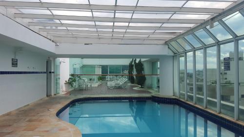 una piscina cubierta en un edificio con ventanas en Apartamento Temporada Guarujá Four Seasons, en Guarujá