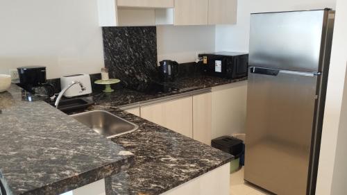 a kitchen with granite counter tops and a stainless steel refrigerator at Leviosa- departamento nuevo con parrilla en el balcón in Puerto Madryn