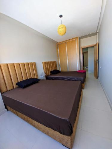 a bedroom with two beds and a light fixture at Green Haven Near Airport Stay in Deroua