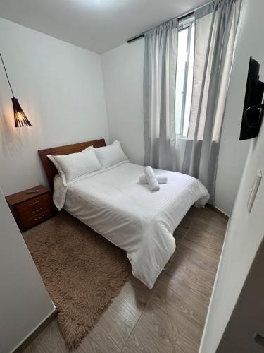a small bedroom with a white bed and a window at Habitaciones privadas cerca al aeropuerto in Armenia