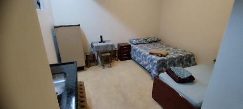 a small room with two beds and a desk at Suítes independentes com acesso independente e privativo in Lavras