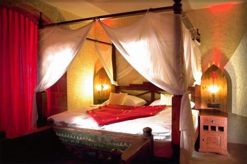 een slaapkamer met een hemelbed en rode gordijnen bij BinzHotel Landhaus Waechter in Binz