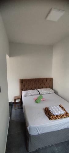 a bedroom with a bed with white sheets and a blanket at Suítes independentes com acesso independente e privativo in Lavras