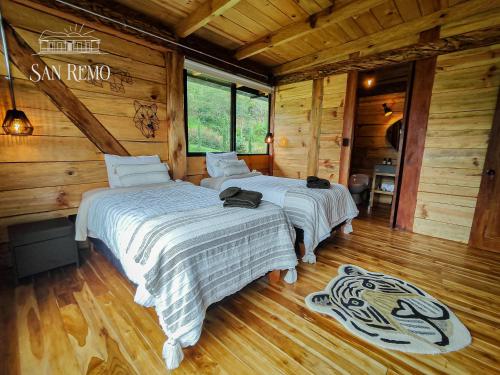 two beds in a room with wooden walls and wood floors at Hotel Rural SAN REMO in Santa Rosa de Cabal