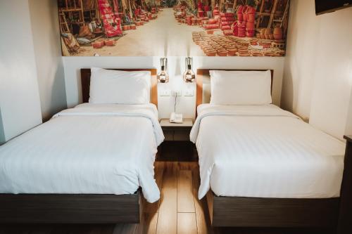 two beds in a small room with a painting on the wall at GQ Plaza in Kalibo