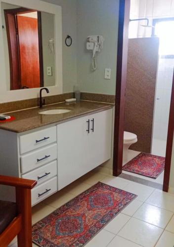 a bathroom with a sink and a mirror and a toilet at AREIA DE TAPERAPUAN - 200 MTS da PRAIA - ORLA NORTE in Porto Seguro