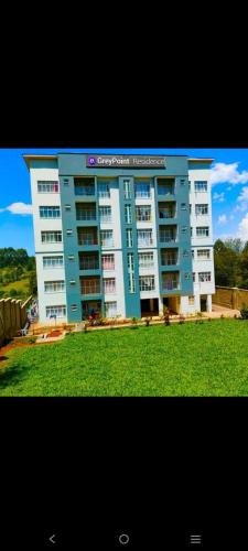 a large apartment building in front of a green field at Zoe Homes Greypoint 1 bedroom apartment 301 in Kericho
