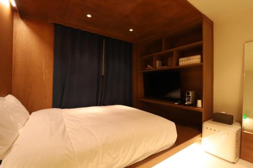 a bedroom with a white bed and a book shelf at lyrical Hotel Cheongju in Cheongju