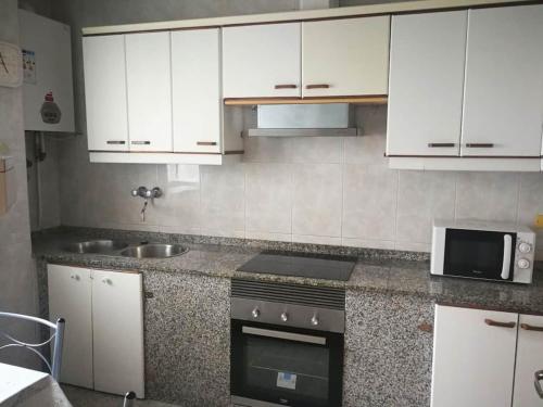 a kitchen with white cabinets and a stove top oven at Casa rias baixas in Poio