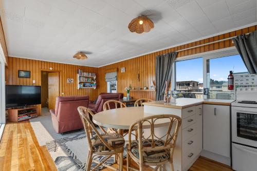 a kitchen and living room with a table and chairs at Kiwi Beach Bach - Waihi Beach Holiday Home in Waihi Beach
