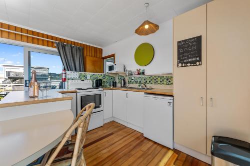 a kitchen with white cabinets and a chalkboard on the wall at Kiwi Beach Bach - Waihi Beach Holiday Home in Waihi Beach