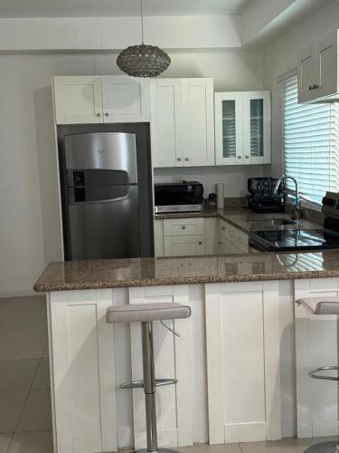 a kitchen with white cabinets and a stainless steel refrigerator at Harloes Suites - Kingston - Free Parking and Pool in Kingston