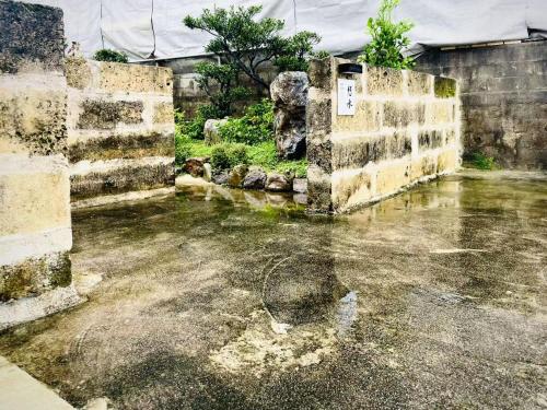 an old building with water in a yard at 田舎の静かな古民家の悠水居 in Itoman