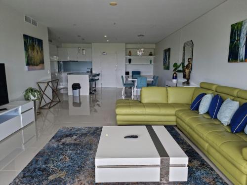 a living room with a green couch and a table at Cairns Private Apartments in Cairns