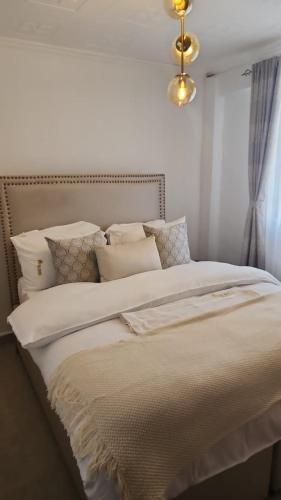 a bedroom with a large bed with white sheets and pillows at Zoe Homes Oak Villa Apartment 1 and 2 Bedroom 201 in Kericho