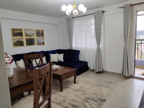 a living room with a blue couch and a table at Zoe Homes Oak Villa Apartment 1 and 2 Bedroom 201 in Kericho